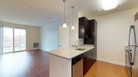 This single-floor, 2-bedroom, 2-bathroom residence offers a thoughtfully designed open-concept layout that maximizes functionality and flow. The kitchen serves as a central focal point, featuring dark espresso cabinetry that contrasts elegantly with light granite countertops. A peninsula island with an undermount sink provides additional prep space and casual seating potential, while stainless steel appliances, including a dishwasher, add a modern, polished touch. Dual pendant lights hang above the peninsula, providing focused task lighting with a contemporary aesthetic.

The kitchen opens seamlessly into the living area, creating a connected and sociable space suited for both everyday living and entertaining. Warm hardwood-style flooring flows throughout the main living areas, adding a cohesive and inviting feel to the space. Neutral white walls provide a versatile backdrop, allowing for a variety of décor styles. The living area benefits from natural light, contributing to an airy and open ambiance. Overall, the residence combines modern design elements with practical features, offering a clean, comfortable, and move-in-ready living environment.