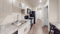 Located at 3561 Milledgeville Rd in Augusta, Georgia, this single-floor unit offers a well-designed, contemporary layout with consistent wood-look flooring and a neutral color palette that creates a cohesive, modern aesthetic throughout.

The open-concept living area flows seamlessly into the kitchen, providing a practical and inviting layout. The kitchen is outfitted with white cabinetry featuring black hardware, granite-style countertops, a stainless steel sink, and black appliances including a refrigerator, electric range, microwave, and dishwasher. Recessed lighting illuminates the space efficiently.

The living space is generously sized, featuring a ceiling fan with integrated lighting and recessed fixtures. Its open design accommodates both a lounge and sleeping area, offering versatility and comfort.

The bathroom is clean and functional, featuring a shower-tub combination with a curtain rod, a vanity with granite-style countertops and ample cabinet storage, and a toilet. Decorative framed artwork and coordinating accessories add a polished finishing touch.

Throughout the unit, the warm wood-look flooring ties each space together, while the bright, neutral walls enhance the sense of openness. The overall design is modern, practical, and well-appointed, making it a functional living space in Augusta, GA.