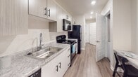 Located at 3561 Milledgeville Rd in Augusta, Georgia, this single-floor unit offers a well-designed, contemporary layout with consistent wood-look flooring and a neutral color palette that creates a cohesive, modern aesthetic throughout.

The open-concept living area flows seamlessly into the kitchen, providing a practical and inviting layout. The kitchen is outfitted with white cabinetry featuring black hardware, granite-style countertops, a stainless steel sink, and black appliances including a refrigerator, electric range, microwave, and dishwasher. Recessed lighting illuminates the space efficiently.

The living space is generously sized, featuring a ceiling fan with integrated lighting and recessed fixtures. Its open design accommodates both a lounge and sleeping area, offering versatility and comfort.

The bathroom is clean and functional, featuring a shower-tub combination with a curtain rod, a vanity with granite-style countertops and ample cabinet storage, and a toilet. Decorative framed artwork and coordinating accessories add a polished finishing touch.

Throughout the unit, the warm wood-look flooring ties each space together, while the bright, neutral walls enhance the sense of openness. The overall design is modern, practical, and well-appointed, making it a functional living space in Augusta, GA.