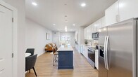 Located at 144 N Main St in Dublin, PA, this one-bedroom, two-bathroom residence offers a thoughtfully designed single-floor layout with modern finishes throughout. The open-concept living and kitchen area forms the heart of the home, featuring light hardwood flooring, recessed lighting, and neutral wall tones that create a bright, clean aesthetic. A sliding glass door opens to a private balcony, allowing natural light to fill the living space and providing pleasant outdoor views.

The kitchen is well-appointed with white shaker-style cabinetry extending to the ceiling, white quartz countertops, a classic subway tile backsplash, and a full suite of stainless steel appliances including a side-by-side refrigerator, electric range, built-in microwave, and dishwasher. A navy blue island adds a distinctive design accent and provides additional counter space.

The bedroom is a calm retreat finished with the same warm hardwood flooring and neutral tones, with direct access to one of the two bathrooms. That bathroom features a dual-sink vanity with white cabinetry, quartz countertops, and tile flooring. A spacious closet with wire shelving provides ample storage. The layout also includes a hallway leading to a second bathroom, offering added convenience for guests.