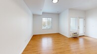 Located at 7550 N Lombard St in Portland's St. Johns neighborhood, this efficiently designed unit offers a well-organized layout across a single floor. Warm-toned hardwood flooring runs throughout the space, lending a cohesive and inviting feel to every room.

The kitchen is a standout feature, outfitted with crisp white shaker-style cabinetry, a classic white subway tile backsplash, stainless steel appliances including a refrigerator, electric range, and dishwasher, and a single-basin sink. The clean, functional design maximizes every inch of counter and storage space.

The main living area is bright and open, with white walls and multiple windows that invite natural light and provide views of the surrounding neighborhood. A wall-mounted AC unit ensures year-round comfort. Recessed and flush-mount ceiling lighting keeps the space well-lit throughout.

The hallway connects the living area to the bathroom and closet. A louvered sliding closet door conceals a stacked washer/dryer unit, adding in-unit laundry convenience. An electrical panel is also accessible from the hallway.

The bathroom features full white subway tile surrounding a soaking tub and shower combination, a toilet, vanity with mirror, and a grab bar, reflecting a clean, modern aesthetic. The unit offers a practical and comfortable living environment in a well-maintained building.