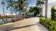 Located at 4335 NW 18th St in Miami, FL, this single-story property presents a compelling blend of South Florida architectural character and resort-inspired outdoor living. The exterior facade features a clean stucco finish with bold orange accent elements and arched architectural details, framed by an abundance of mature palm trees and tropical greenery that reinforce the property's warm, Miami aesthetic.

At the heart of the outdoor space is a generously sized swimming pool with crystal-clear blue water, surrounded by a spacious concrete deck ideal for lounging. Adjacent to the pool, a dedicated waterfront relaxation area offers lounge chairs, shaded umbrellas, and wooden seating overlooking a serene canal — all enclosed by decorative iron fencing. The tropical canopy of swaying palms provides natural shade and enhances the tranquil atmosphere.

The property is accessed through a modern sliding metal gate that opens to a courtyard entrance framed by large glass-panel doors, a wood pergola overhead, and well-maintained landscaping with red mulch beds and manicured shrubs. Thoughtfully designed walkways connect the various outdoor zones, creating a cohesive and functional layout throughout the grounds. This property offers a quintessential South Florida outdoor experience with strong visual appeal and practical amenities.