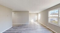 Located at 901 N Main St in Mauldin, SC, this single-story, 2-bedroom, 1-bathroom home offers a thoughtfully arranged layout with modern finishes throughout. Light gray luxury vinyl plank flooring runs continuously through every room, creating a cohesive and easy-to-maintain foundation. Neutral warm-beige walls and white trim provide a clean, move-in-ready aesthetic throughout the space.

The living room is generously proportioned, featuring multiple windows that allow abundant natural light to fill the space. A textured ceiling adds subtle architectural character to the area.

The galley-style kitchen is well-appointed with crisp white shaker cabinetry, quartz countertops, a double-basin stainless steel sink with a gold-toned faucet, and stainless appliances including a refrigerator and dishwasher. Ample upper and lower cabinet storage makes the kitchen both functional and visually appealing.

Both bedrooms are comfortably sized, with the primary bedroom offering notable square footage. Each room includes closet storage — one bedroom features a built-in closet with shelving and a bi-fold door. Windows in both bedrooms provide natural light and views of the surrounding neighborhood.

The bathroom includes a quartz-top vanity, louvered cabinet, and towel bar, maintaining the home's consistent modern styling. Two hallways and additional closets contribute to practical storage throughout.