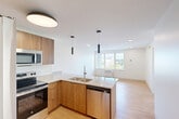 Located at 300 W Sixth St in Chattanooga, TN, this well-appointed 2-bedroom, 2-bathroom residence offers a thoughtfully designed single-floor layout with a clean, modern aesthetic. Light wood flooring runs throughout, complementing the bright white walls and creating a warm, cohesive atmosphere.

The open-concept kitchen and living area serves as the heart of the unit. The kitchen is outfitted with warm wood cabinetry, speckled granite countertops, a large peninsula island with a double stainless steel sink, and a full suite of stainless steel appliances including a refrigerator, electric range, built-in microwave, and dishwasher. Sleek pendant lighting accents the island, adding a modern touch.

The living area flows seamlessly from the kitchen and is bathed in natural light from a large picture window offering outdoor views of the surrounding Chattanooga cityscape. Both bedrooms are well-sized, with the primary bedroom providing a comfortable footprint, large windows, and access to a closet. The second bedroom features the same light flooring and clean lines. Each of the two bathrooms is finished with granite-topped wood vanities, tiled shower-tub combinations, and chrome fixtures. A hallway connects the private quarters, with two closets offering practical storage throughout.