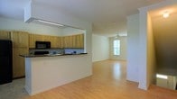 This multi-floor space spans three levels and is designed with an open, airy layout that promotes a seamless flow between living areas. The main living space features warm hardwood flooring that extends throughout, creating a cohesive and inviting atmosphere. The kitchen is equipped with light maple cabinetry, dark countertops, and built-in appliances including a microwave and range. A convenient pass-through counter connects the kitchen to the open living and dining area, making it ideal for everyday living and entertaining. The living area benefits from abundant natural light streaming through a prominent window, further enhanced by a ceiling fan that adds both comfort and a decorative touch. Crown molding along the ceilings adds a refined architectural detail throughout the space. The clean white walls and neutral tones create a versatile backdrop that complements a variety of interior styles. With three floors, the space offers ample room for flexible use, whether for living, working, or hosting guests. The overall ambiance is bright, clean, and functional, reflecting a thoughtfully designed interior that balances practicality with comfortable living.