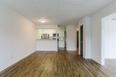 This single-floor residence in Atlanta, GA (30339) offers a thoughtfully designed layout with a cohesive mix of updated finishes and functional spaces throughout. The entryway, framed by a bold black front door, transitions smoothly into the main living areas via wood-look laminate flooring that extends through much of the unit.

The living room is a generously sized, open space featuring a textured ceiling, natural light from a side window, and direct access to a private outdoor deck through sliding glass doors dressed with vertical blinds. The deck overlooks a lush, wooded backdrop, providing a tranquil outdoor retreat.

The kitchen is well-equipped with white shaker cabinetry, granite-style countertops, white subway tile backsplash, and stainless steel appliances including a range, over-the-range microwave, and refrigerator. A pass-through counter connects the kitchen to the adjacent living area, enhancing the open feel.

The bedroom features plush carpeting, a ceiling fan with light fixture, and a window for natural light. It connects directly to a bathroom appointed with a white vanity, granite countertop, and a tiled tub-shower combination with brushed nickel fixtures. Wood-look flooring carries through the bathroom for a consistent finish.
