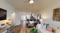 Located at 3510 Corder Dr in Wilmington, NC, this two-story home offers a thoughtfully designed layout with modern finishes and functional living spaces across both levels. The main floor centers around an open-concept living, dining, and kitchen area, unified by rich hardwood-style flooring. The living room is bright and welcoming, with large windows that invite natural light, a ceiling fan, and a wall-mounted TV area with easy access to the entryway staircase. The kitchen is equipped with stainless steel appliances, granite countertops, a subway tile backsplash, and a mix of white upper and gray lower cabinetry. A peninsula with bar seating connects the kitchen seamlessly to the living and dining areas. Also on the main level is a dedicated laundry closet housing a full-size washer and dryer, tucked behind double doors for convenience. Upstairs, carpeted bedrooms provide comfortable retreats. The primary bedroom features a shiplap accent wall, ceiling fan, and a walk-in closet. A secondary bedroom offers a charming arched wall detail and a bright window with neighborhood views. The bathroom is finished with granite countertops, white cabinetry, hardwood-style flooring, and clean, neutral tones. A carpeted staircase with white-painted railings connects both floors with classic charm.