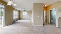 Located at 1211 Seventh Ave S in Sartell, Minnesota, this single-floor unit offers a well-organized and functional layout designed for comfortable everyday living. The open-concept living and dining area is generously proportioned, featuring plush wall-to-wall carpeting, warm neutral-toned walls, a ceiling fan, and large windows with vertical blinds that allow abundant natural light to fill the space. A sliding glass door connects the dining area to an outdoor space, enhancing the sense of openness. The kitchen is outfitted with rich dark-wood cabinetry, granite-style countertops, stainless steel appliances including a range, microwave, and refrigerator, and a peninsula with pendant lighting that creates a seamless connection to the living area. Tile flooring adds a practical touch to this cooking space. The bedrooms are carpeted and finished in soft neutral tones; one features a spacious walk-in closet with built-in shelving. The bathrooms include tile flooring, a vanity with a large mirror, brushed nickel fixtures, and one features a standalone walk-in shower. Baseboard heating is present throughout, ensuring consistent warmth. The overall aesthetic is clean, neutral, and move-in ready.