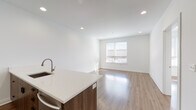 Located at 301 George St in New Haven, CT, this single-floor unit showcases a clean, modern design with a cohesive aesthetic throughout. A wide hallway entrance leads into the heart of the space, where an open-concept kitchen and living area form the central gathering space. The kitchen is outfitted with wood-toned cabinetry, a quartz waterfall island with an undermount sink, stainless steel appliances including a refrigerator and microwave, and recessed lighting overhead. The adjoining living area benefits from natural light through a large window and features polished hardwood-style flooring that runs continuously throughout the unit.

The bedrooms are bright and well-proportioned, each receiving natural light from individual windows with blinds. Closet access is thoughtfully integrated, and the rooms maintain the same clean, neutral palette found throughout the space. A wall-mounted split AC unit ensures climate control comfort.

The primary bathroom features a double-sink vanity with dark wood cabinetry, a large mirror, tile flooring, and a glass-enclosed tub and shower combination. A dedicated laundry area houses a full-size side-by-side washer and dryer with overhead storage cabinetry, adding practical convenience to the unit's overall well-appointed design.