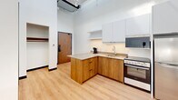 Located at 601 Scottsdale Dr in Guelph, Ontario, this efficiently designed two-bedroom, one-bathroom unit offers a clean, modern aesthetic throughout its single floor. The open-concept kitchen anchors the living space, featuring warm wood cabinetry, light stone countertops with a built-in breakfast bar, white upper cabinets with under-cabinet lighting, and stainless steel appliances including a range and microwave. Light hardwood flooring runs through the kitchen and main area, lending a warm, contemporary feel.

Both bedrooms are thoughtfully laid out, each equipped with a wood-framed bed with under-bed storage drawers, a built-in desk and floating shelf, a wall-mounted flat-screen television, and a window offering outdoor views. Recessed lighting and neutral carpet flooring give each room a calm, functional atmosphere well-suited for study and rest.

The bathroom is finished with floor-to-ceiling white subway tile in a spacious glass-enclosed walk-in shower, complemented by dark matte grab bars and a sleek floor drain. Dark floor tiles complete the clean, accessible design.

Throughout the unit, crisp white walls, recessed lighting, and consistent modern furnishings create a cohesive and practical living environment suited for students or young professionals.