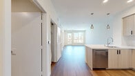 Located at 549 S Hobart Blvd in the heart of Los Angeles, this modern 2-bedroom, 1-bathroom unit offers a thoughtfully designed single-floor layout with contemporary finishes throughout. The open-concept kitchen and living area serves as the heart of the home, featuring light wood-tone cabinetry with black hardware, stainless steel appliances including a gas range, microwave, dishwasher, and a full-size refrigerator. A central kitchen island with a clean white countertop and pendant lighting above adds both style and function to the space. Wood-style flooring flows seamlessly throughout the unit, lending a warm, cohesive aesthetic. The primary bedroom is bathed in natural light through large windows and a glass-paneled door that opens directly onto a private balcony, offering open views of the Los Angeles skyline, palm trees, and the building's pool area below. Both bedrooms feature clean white walls, wood flooring, and sliding closet doors for ample storage. The bathroom is finished with large-format tile flooring, a soaking tub, and a tiled surround, maintaining a clean and minimal design. The private balcony extends the living space outdoors, providing a scenic vantage point over the surrounding neighborhood.