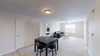 This single-floor residence offers a functional and comfortable layout across several well-defined living spaces. The open-plan living and dining area serves as the heart of the home, featuring soft carpeted flooring, neutral cream-toned walls, and a ceiling fan that enhances airflow and comfort. Natural light filters in through window blinds, creating a bright and welcoming atmosphere. The dining space accommodates a four-seat table, while the living area provides ample room for seating and relaxation.

The kitchen is designed for practicality, featuring warm oak cabinetry with generous storage, light countertops, a double-basin sink, and a suite of black appliances including an electric range, over-the-range microwave, and dishwasher. Tile flooring ties the space together cleanly.

The residence includes three bedrooms, each carpeted and equipped with ceiling fans and windows that bring in natural light. The rooms are comfortably sized, offering sufficient space for a bed and additional furnishings.

Two bathrooms serve the unit — one featuring a full shower/tub combination and the other functioning as a half or secondary bath — both finished with tile flooring, warm wood vanities, and chrome hardware accents throughout.