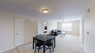 This single-floor residence offers a functional and comfortable layout across several well-defined living spaces. The open-plan living and dining area serves as the heart of the home, featuring soft carpeted flooring, neutral cream-toned walls, and a ceiling fan that enhances airflow and comfort. Natural light filters in through window blinds, creating a bright and welcoming atmosphere. The dining space accommodates a four-seat table, while the living area provides ample room for seating and relaxation.

The kitchen is designed for practicality, featuring warm oak cabinetry with generous storage, light countertops, a double-basin sink, and a suite of black appliances including an electric range, over-the-range microwave, and dishwasher. Tile flooring ties the space together cleanly.

The residence includes three bedrooms, each carpeted and equipped with ceiling fans and windows that bring in natural light. The rooms are comfortably sized, offering sufficient space for a bed and additional furnishings.

Two bathrooms serve the unit — one featuring a full shower/tub combination and the other functioning as a half or secondary bath — both finished with tile flooring, warm wood vanities, and chrome hardware accents throughout.