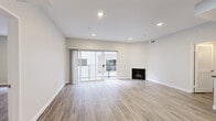 This well-designed 2-bedroom, 2-bathroom single-floor residence offers a clean, modern aesthetic throughout, unified by light wood-style flooring and a crisp neutral color palette. The open living room is a standout feature, anchored by a black-framed fireplace and sliding glass doors that open onto a private balcony, filling the space with natural light. Recessed lighting overhead adds a polished finish to the room.

The kitchen is thoughtfully appointed with white shaker cabinetry, gray countertops, a classic subway tile backsplash, and a full suite of stainless steel appliances including a gas range, over-the-range microwave, and refrigerator.

The spacious primary bedroom features its own sliding glass door to the balcony and leads directly into a dedicated walk-in closet outfitted with built-in shelving and hanging rods. The second bedroom is generously sized with a large window and access to a sizable closet as well.

Both bathrooms maintain a consistent modern style with white cabinetry, gray countertops, and light wood-style flooring. One bathroom includes a shower-tub combination with sleek black fixtures, while the second offers a refined, streamlined layout. A connecting hallway ties all rooms together, completing this cohesive and functional floor plan.