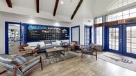This 2,470 square foot fitness center is a modern, well-equipped facility designed to cater to a variety of exercise needs. The space is characterized by its vaulted ceilings with exposed wooden beams, which add a sense of spaciousness and architectural interest. Large, blue-framed windows allow ample natural light to flood the interior, creating a bright and invigorating atmosphere.

The main workout area features a comprehensive selection of cardio and strength training equipment, including treadmills, ellipticals, weight machines, and free weights. The floor is covered with durable, easy-to-clean materials suitable for high-traffic gym environments.

Adjacent to the main gym, there's a multipurpose room with hardwood flooring, perfect for group classes or stretching. This area is equipped with a large mirror wall and features motivational signage, fostering a positive and encouraging environment.

The facility also includes a comfortable lounge area with modern furnishings, providing a space for members to relax or socialize. A dedicated computer station offers convenience for members who need to work or check emails.

The center's design incorporates a blue and white color scheme throughout, creating a cohesive and professional look. Attention to detail is evident in the carefully chosen fixtures, including modern ceiling fans and recessed lighting.

Overall, this fitness center combines functionality with aesthetic appeal, offering a welcoming and motivating space for health and wellness activities.