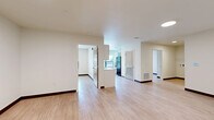 Located at 2732 Forest Ave in Kansas City, MO, this 2-bedroom, 1-bathroom unit offers a clean, modern interior with a practical and efficient layout. Light wood-style flooring runs throughout the entire space, complemented by crisp white walls and dark baseboards that provide a polished, contemporary look.

The combined kitchen and living area serves as the heart of the unit. The kitchen is well-appointed with white cabinetry featuring black hardware, light countertops, a stainless steel sink, and black appliances including a range, dishwasher, and full-size refrigerator. A large window above the kitchen area fills the space with natural light and offers views of the surrounding neighborhood's greenery.

The open living area provides a generous, flexible space with recessed lighting and direct access to the unit's entry door. Both bedrooms are comfortably sized, each featuring natural light from windows with views of the outdoors and built-in open shelving closets for ample storage. The primary bedroom includes a particularly spacious closet layout with multiple shelving tiers.

The full bathroom is neatly finished with white cabinetry, a vanity mirror, a single-basin sink, and a full tub-shower combination. A connecting hallway ties all rooms together, creating a cohesive and functional flow throughout the unit.