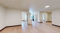 Located at 2732 Forest Ave in Kansas City, MO, this 2-bedroom, 1-bathroom unit offers a clean, modern interior with a practical and efficient layout. Light wood-style flooring runs throughout the entire space, complemented by crisp white walls and dark baseboards that provide a polished, contemporary look.

The combined kitchen and living area serves as the heart of the unit. The kitchen is well-appointed with white cabinetry featuring black hardware, light countertops, a stainless steel sink, and black appliances including a range, dishwasher, and full-size refrigerator. A large window above the kitchen area fills the space with natural light and offers views of the surrounding neighborhood's greenery.

The open living area provides a generous, flexible space with recessed lighting and direct access to the unit's entry door. Both bedrooms are comfortably sized, each featuring natural light from windows with views of the outdoors and built-in open shelving closets for ample storage. The primary bedroom includes a particularly spacious closet layout with multiple shelving tiers.

The full bathroom is neatly finished with white cabinetry, a vanity mirror, a single-basin sink, and a full tub-shower combination. A connecting hallway ties all rooms together, creating a cohesive and functional flow throughout the unit.