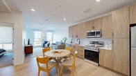This thoughtfully designed one-bedroom, one-bathroom residence in Denver's South Acoma Street neighborhood offers a modern open-concept layout that maximizes every inch of its well-appointed floor plan. Light hardwood flooring flows throughout the main living areas, complementing the clean, contemporary aesthetic.

The kitchen is a standout feature, showcasing warm wood-grain cabinetry extending to the ceiling, white quartz countertops, a geometric tile backsplash, matte black fixtures, and a full suite of stainless steel appliances including a range, microwave, and dishwasher. The kitchen opens directly to a dining area and a bright living room, which is anchored by large windows that invite generous natural light and outdoor views.

The bedroom offers a calm retreat with plush carpeting, a wide window with roller shades, and a relaxed, neutral palette. The full bathroom is elegantly finished with a wood-toned double vanity, white quartz countertop, matte black hardware, a wide backlit mirror, and a glass-enclosed tiled shower. A hallway connects the rooms efficiently, completing the smart layout. This residence delivers a refined, contemporary living experience in a sought-after Denver location.