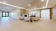 Located at 3271 Hilltown Dr in Kelowna, BC, this well-appointed common area space spans a single floor and offers a cohesive blend of modern and classic design elements. The space is composed of three distinct hallway and lounge zones, each showcasing careful attention to detail and high-quality finishes.

The primary lounge area is a standout feature, highlighted by a stunning wood-planked ceiling with integrated ambient lighting that creates a warm, inviting atmosphere. A sleek fireplace framed in brushed gold anchors the room, while light hardwood flooring runs throughout, complementing the crisp white walls. Comfortable seating arrangements, including neutral-toned sofas and armchairs, make the space ideal for gathering and relaxation.

The elevator lobby hallway presents a clean, contemporary aesthetic with stainless steel elevator doors, warm wood panel accents, and smooth light hardwood flooring. Flush-mounted circular ceiling fixtures provide consistent, bright illumination along the corridor.

A third hallway stands apart with its decorative mosaic tile flooring featuring intricate geometric patterning, flanked by classic white wainscoting and warm beige upper walls. Double doors at the end of this corridor introduce natural light, reinforcing a sense of openness. Together, these areas form a refined, welcoming environment suited to a residential building's shared common spaces.