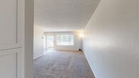 Located at 550 Los Arbolitos Boulevard in Oceanside, California, this single-floor, one-bedroom, one-bathroom unit offers a practical and comfortable layout across a well-utilized footprint. The entrance leads into a combined living and dining area featuring neutral-toned carpet, a textured ceiling, and large windows dressed with horizontal blinds that invite abundant natural light. A ceiling fan enhances the dining area, while a sliding glass door opens to an outdoor patio with views of mature surrounding trees. The galley-style kitchen is a standout feature, showcasing white shaker cabinetry, dark speckled granite countertops, a white subway tile backsplash, black appliances including a gas range and dishwasher, and wood-look flooring that adds warmth and continuity. The bedroom is a well-proportioned retreat with plush carpet, a window overlooking the greenery outside, and a full-width sliding-door closet providing generous storage. The bathroom impresses with a wide dual-sink vanity topped with dark granite counters, white cabinetry with brushed nickel hardware, wood-look flooring, and a clean white tub-shower combination. A dedicated hallway connects the rooms efficiently, completing this well-organized and move-in-ready home.