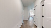 This thoughtfully designed single-story home offers 2 bedrooms and 3 bathrooms within a well-appointed, open layout. The combined kitchen and living area serves as the heart of the home, featuring sleek white cabinetry, quartz countertops, stainless steel appliances, a undermount sink with a matte black faucet, and stylish black pendant lighting. Light wood-style flooring flows consistently throughout the space, complementing the crisp white walls and clean architectural lines.

A welcoming hallway connects the living areas to the private quarters, lined with white panel doors accented by matte black hardware. The generously sized primary bedroom offers a ceiling fan, a large window that invites natural light and outdoor views, and access to a spacious walk-in closet outfitted with multi-tier wire shelving systems. With six closets total across the home, storage is abundant. The second bedroom is equally well-proportioned with its own access to closet space.

A dedicated laundry room comes equipped with a full-size top-load washer and dryer alongside overhead wire shelving for added utility. Recessed lighting throughout enhances the bright, modern ambiance, while consistent finishes and a neutral palette give the entire home a cohesive, contemporary feel.