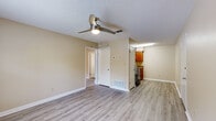 Located at 107 Alder Ave SE in Fort Walton Beach, Florida, this single-story residence offers a practical and well-organized layout with a clean, neutral aesthetic throughout. The main living area features light gray wood-look laminate flooring and a ceiling fan with integrated lighting, creating a bright and airy atmosphere. This space flows conveniently toward the kitchen, which is equipped with warm-toned wood cabinetry, granite-look countertops, a double sink, an electric range, and a dishwasher — all finished with light flooring that complements the living area. The bedrooms are carpeted for comfort and each feature ceiling fans, natural light from windowed walls with blinds, and generous proportions. The primary bedroom includes an attached bathroom and a separate closet. Two full bathrooms serve the home, both appointed with tub-shower combinations, warm wood vanities, light countertops, and mirrored medicine cabinets. Textured ceilings are consistent throughout the home, adding a classic touch. The overall color palette of warm beige tones and white trim lends the space a cohesive, move-in-ready feel well-suited for everyday living in the heart of Fort Walton Beach.