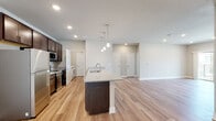 This well-appointed single-floor residence offers a clean, modern aesthetic throughout, anchored by light hardwood flooring and neutral gray tones that create a cohesive and inviting atmosphere. The open-concept layout connects the kitchen and living area seamlessly, making the space feel expansive and functional.

The kitchen is a standout feature, showcasing rich dark cabinetry with brushed nickel hardware, light granite countertops, and a full suite of stainless steel appliances including a refrigerator, range, and built-in microwave. A central island with a sink and pendant lighting above serves as both a prep area and a casual gathering spot, opening directly to the generous living area, which benefits from recessed lighting and a window that invites natural light.

The space includes multiple bedrooms, each finished with the same hardwood flooring and crisp white five-panel doors. The primary bedroom is notably spacious, with a walk-in closet outfitted with wire shelving for organized storage. Two full bathrooms are present — one featuring a tub-shower combo and the other a dedicated walk-in shower — both equipped with dark vanities, granite countertops, and brushed nickel fixtures. A dedicated laundry room with a full-size washer and dryer completes this thoughtfully designed residence.