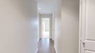 This single-floor residence offers a thoughtfully laid-out floor plan with three bedrooms, two bathrooms, a kitchen, a dedicated closet, and two connecting hallways. The interior presents a clean, contemporary aesthetic defined by neutral tones, light-toned flooring, and crisp white walls throughout.

The kitchen is a functional highlight, featuring warm wood-toned cabinetry in two complementary finishes, white quartz countertops, subway tile backsplash, and stainless steel appliances including a refrigerator, gas range, and built-in microwave. A large window above the double sink invites natural light and frames outdoor views of the surrounding neighborhood and hillside scenery. Track lighting overhead enhances both ambiance and functionality.

The hallways are finished with smooth hardwood-style flooring and recessed lighting, providing clean transitions between spaces. The bedrooms are carpeted in neutral tones, offering a soft, comfortable feel, and include built-in closets with sliding or bi-fold doors for practical storage.

The two bathrooms reflect a modern, minimalist design. One features a soaker tub with a handheld showerhead and large-format white tile surround, while the second offers a glass-enclosed shower stall, a wood-vanity with an integrated sink, and light marble-look tile flooring. Together, they deliver functional elegance in a compact, efficient layout.