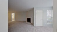 This contemporary apartment offers a blend of comfort and functionality. The living areas boast plush carpeting, light gray walls, and large windows that invite natural light. The bedroom continues this aesthetic, creating a serene atmosphere. The bathroom showcases clean lines with white tiled walls and modern fixtures. A highlight is the walk-in closet with built-in shelving and hanging space. The unit includes a private laundry area with full-sized appliances. The floor plan reveals an efficient layout, maximizing space usage. Throughout, the apartment maintains a cohesive design with neutral tones and sleek finishes, providing a canvas for personal style.