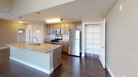 Located at 27000 W Lugonia Ave in Redlands, California, this single-floor residence offers a well-designed, open-concept layout with a seamless flow between the living and kitchen areas. Rich, dark hardwood flooring runs throughout the main living spaces, providing a warm and polished aesthetic against the neutral, taupe-toned walls.

The kitchen is a functional centerpiece, featuring light wood cabinetry, granite countertops, a full suite of stainless steel appliances including a gas range, built-in microwave, and refrigerator, and a mosaic tile backsplash. A peninsula island with a double sink and pendant lighting above creates an ideal space for both meal preparation and casual dining. A built-in shelving unit adjacent to the kitchen provides additional storage.

The open living area benefits from natural light through blinded windows and offers generous space for a variety of furniture arrangements. A hallway leads to the bedroom, which features plush carpeting, a large window with views of the surrounding community, and a dedicated electrical panel. The bathroom is clean and well-appointed, with a full tub-shower combination, granite-topped vanity with wood cabinetry, and hardwood-style flooring. Track and pendant lighting throughout ensure well-lit interiors across the unit.