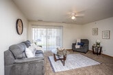 This single-floor residence offers a thoughtfully designed layout that balances comfort and functionality throughout. The living room serves as the heart of the space, featuring plush carpeting, a ceiling fan, and a large sliding glass door flanked by vertical blinds that floods the room with natural light and provides direct outdoor views. The open, airy atmosphere makes it an inviting area for relaxation and entertaining.

Adjacent to the living area, the dining space features tile flooring and provides a natural transition from the kitchen, offering a welcoming spot for everyday meals. The kitchen is well-equipped with warm oak cabinetry offering generous storage, laminate countertops, a double-basin stainless steel sink, a black electric range with overhead ventilation, and a dishwasher — delivering a practical and efficient cooking environment.

The bedrooms are carpeted and comfortably sized, each featuring windows with vertical blinds that allow for natural light and outdoor views. Closet space is conveniently integrated into the bedroom areas. The full bathroom includes tile flooring, an oak vanity with a wide mirror, and a tub/shower combination, completing the space with a clean, functional design. Warm wood trim and neutral wall tones carry consistently throughout, lending the residence a cohesive and welcoming character.