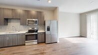Located at 4301 Dominion Forest Circle in Glen Allen, Virginia, this one-bedroom, one-bathroom residence offers a thoughtfully designed single-level layout with a cohesive modern aesthetic throughout. Rich hardwood-style flooring runs continuously across the living areas, bedroom, and bathroom, lending warmth and visual continuity to the space.

The kitchen is a standout feature, showcasing dark wood-grain cabinetry, white quartz-style countertops, a subway tile backsplash, and a full suite of stainless steel appliances including a side-by-side refrigerator with ice maker, electric range, built-in microwave, and dishwasher. The kitchen opens directly to the living room, creating an efficient and connected layout.

The living room receives generous natural light through a large sliding glass door fitted with vertical blinds, which leads out to a private balcony with views of the surrounding community. The bedroom is a comfortable, well-proportioned retreat with a ceiling fan, a window with blinds, and access to a spacious walk-in closet outfitted with wire shelving systems for organized storage.

The bathroom features dark cabinetry with a white countertop vanity, a large mirror, and a glass-enclosed walk-in shower with tile surround. Neutral warm-gray paint tones throughout the residence create a clean, move-in-ready ambiance.