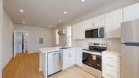 Located at 1736 Ramjet Point in Colorado Springs, CO, this efficiently designed single-floor unit offers a thoughtfully arranged open-concept layout that maximizes every inch of its compact footprint. Light wood-tone luxury vinyl plank flooring runs throughout, creating a warm and cohesive look across the entire space.

The kitchen is a standout feature, outfitted with crisp white shaker-style cabinetry, sleek brushed nickel hardware, and a full suite of stainless steel appliances including a refrigerator, electric range, built-in microwave, and dishwasher. A peninsula with a single-basin sink and white countertops provides both prep space and a natural divider between the kitchen and the open living area. Recessed lighting illuminates the kitchen, while multiple windows fitted with horizontal blinds allow abundant natural light to fill the space and offer views of the surrounding neighborhood.

A wall-mounted HVAC unit provides climate control for the main living area. The bathroom features light, neutral tones with a white vanity, a tub-shower combo with built-in shelving, a curved curtain rod, and a window that brings in additional natural light. The overall aesthetic is clean, modern, and move-in ready, making this unit an efficient and functional living space.