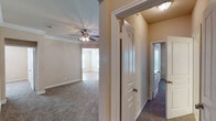 This single-floor residence offers a well-organized layout designed for comfortable everyday living. The kitchen is a functional galley-style space featuring light wood cabinetry, dark countertops with a rich wood-toned edge detail, tile backsplash, hardwood-style flooring, and white appliances including a refrigerator, electric range, microwave, and dishwasher. A peninsula counter provides additional workspace and a natural transition to the adjacent living areas.

The bedrooms are carpeted throughout and finished with neutral warm-toned walls. Each room is equipped with a ceiling fan with lighting, and windows with blinds allow natural light to filter in. One bedroom features crown molding, adding a refined architectural detail. A hallway connects the bedrooms and provides easy access to the bathrooms.

Two bathrooms serve the unit. One includes a neo-angle glass-enclosed stand-up shower, a single-sink vanity with a wood cabinet base, and tile flooring. The second bathroom offers a single-sink vanity with a large mirror, tile flooring, and a shower-tub combination. Both are finished in neutral tones with clean, practical fixtures.

A dedicated utility closet houses the water heater and provides space for laundry connections. The overall ambiance of the space is clean, neutral, and move-in ready.