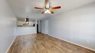 This single-floor home offers a well-designed open-concept layout that seamlessly connects the living, dining, and kitchen areas. The spacious living room is finished with warm wood-look laminate flooring and features a ceiling fan with integrated lighting, complemented by a textured ceiling. Soft, neutral gray walls create a calm and cohesive atmosphere throughout. The dining area is distinguished by a stylish pendant chandelier and a window that invites natural light into the space.

The kitchen is thoughtfully appointed with crisp white cabinetry, granite-style countertops, a stainless steel single-basin sink with a pull-down faucet, a dishwasher, and a black refrigerator. The kitchen opens directly to the living and dining areas via a raised breakfast bar, making it ideal for both everyday use and entertaining.

The bedroom offers plush carpeting, a ceiling fan, and a window with views of the surrounding greenery, creating a quiet and comfortable retreat. The bathroom is clean and functional, featuring wood-look flooring, a white vanity with granite-style countertop, a mirrored medicine cabinet, and a shower-tub combination. The consistent use of neutral tones and updated finishes throughout the space contributes to a cohesive, move-in-ready feel.