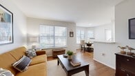 This single-floor, 2-bedroom, 2-bathroom residence offers a thoughtfully designed layout that maximizes comfort and functionality. The open-plan living area is bathed in natural light from large windows fitted with blinds, and features warm hardwood-style flooring that carries throughout the main living spaces. The living room provides a welcoming atmosphere with generous wall space and a front entry door, flowing seamlessly into the dining area, which is brightened by multiple windows on two walls — ideal for everyday meals or entertaining.

The galley-style kitchen is efficiently arranged with warm wood cabinetry, white appliances including a range, refrigerator, and dishwasher, and light countertops. A bonus laundry area with full-size washer and dryer is conveniently accessible directly from the kitchen.

The primary bedroom is a comfortable retreat, featuring a sliding glass door that opens to an outdoor view, vertical blinds, and plush carpeting. The second bedroom also offers carpeted flooring, a ceiling fan, and vaulted ceiling lines that lend a sense of openness.

Both bathrooms are finished with wood-tone vanity cabinetry, white countertops, and a tub-shower combination with tile surround. Two closets provide practical storage, and a hallway connects the private and shared areas of the home cohesively.