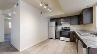 This single-floor, 2-bedroom, 1-bathroom residence offers a thoughtfully organized layout that makes efficient use of its space. The kitchen is a standout feature, showcasing dark espresso cabinetry, stainless steel appliances including a refrigerator, gas range, and dishwasher, complemented by granite-look countertops and light wood-look flooring. A track lighting fixture overhead adds a modern touch, and a window allows natural light to brighten the space. The living area flows naturally from the kitchen, providing a versatile open feel.

Both bedrooms are finished with plush wall-to-wall carpeting and feature neutral, light-toned walls that create a calm and restful atmosphere. The primary bedroom includes a closet with a built-in rod and shelf for organized storage, while windows in the bedrooms invite natural light and outside views. The second bedroom is equally well-sized and bright.

The bathroom is elegantly appointed with marble-patterned tile surround in the tub and shower combination, wood-look tile flooring, a dark vanity cabinet with a granite-look countertop, and a large mirror. A hallway and closet round out the layout, adding to the overall functionality of this well-designed residence.