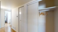 This single-story residence located along Gateway West Boulevard in El Paso, Texas, offers a practical and well-organized layout across its living spaces. The floor plan, visible in the overhead 3D rendering, reveals a clear separation between the living, dining, bedroom, and bathroom areas, providing a functional flow throughout the unit.

The living area features plush carpeting and a ceiling light fixture, transitioning seamlessly into the dining space, which is finished with wood-look flooring. A low dividing partition separates the two areas, adding subtle architectural definition. The dining space accommodates a table and chairs comfortably, with a built-in ledge providing a decorative display surface.

The kitchen is equipped with white cabinetry extending to the ceiling, offering generous storage. White appliances include a gas range with overhead ventilation and a full-size refrigerator, complemented by ample counter space and wood-look flooring.

The bedroom is a well-proportioned, carpeted room with a window that allows natural light to enter. A hallway closet features sliding panel doors with built-in hanging rods and shelving for organized storage.

The bathroom includes wood-look flooring, a white vanity with countertop space, a large mirror, and a separate water closet with a tub-shower combination. The overall interior maintains a clean, neutral palette throughout.