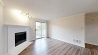 Located in Kirkland, WA, this one-bedroom, one-bathroom residence offers a well-organized single-level layout designed for comfortable everyday living. The combined kitchen and living area forms the heart of the home, where warm hardwood-style flooring, crown molding, and a ceiling fan create an inviting atmosphere. A fireplace anchors the living room, which opens directly to a private balcony through sliding glass doors, bringing in generous natural light and peaceful views of the surrounding greenery. Track lighting adds a modern touch overhead.

The galley-style kitchen is well-appointed with warm wood cabinetry, white quartz countertops, a stainless steel sink, and a full suite of stainless steel appliances, including a dishwasher, refrigerator, and range. A skylight brightens the kitchen corridor, enhancing the sense of openness throughout.

The spacious bedroom features plush carpeting, a large mirrored closet, a baseboard heater, and a window overlooking the lush landscape outside. The full bathroom includes warm wood vanity cabinetry, a white quartz countertop, a combined tub and shower, and hardwood-style flooring. Crown molding and clean white walls carry a consistent, refined aesthetic throughout the entire residence.