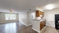 Located at 6355 Oakley Rd in Union City, Georgia, this single-floor home offers two bedrooms and two bathrooms within a generously sized layout. The living room is bright and open, featuring wood-look laminate flooring, a ceiling fan with light fixture, a textured ceiling, and large windows that invite natural light and views of the surrounding greenery. The kitchen is designed for functionality, featuring warm honey-toned cabinetry, grey laminate countertops, a double-basin sink, and black appliances including a refrigerator and electric range. A pass-through counter connects the kitchen to the adjacent living area, enhancing the open feel. Both bedrooms are well-proportioned, each equipped with a ceiling fan, wood-look flooring, and windows fitted with blinds for privacy and light control. The two bathrooms are clean and simply appointed, each offering a tub-shower combination, wood-look tile flooring, and warm wood vanity cabinetry. A dedicated closet provides additional storage. A private balcony overlooks a paved parking area framed by mature trees, offering a pleasant outdoor retreat. The overall aesthetic is neutral and move-in ready throughout.