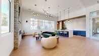 The Encore Clubhouse in Folsom, CA is a thoughtfully designed community facility that seamlessly blends contemporary aesthetics with practical amenities across a single, generously proportioned floor. The entry hallways set the tone immediately, featuring soaring ceilings, light wood flooring, curated large-format artwork, and a mailroom station — creating a polished and welcoming first impression.

The central living room serves as the social heart of the clubhouse. It boasts dramatic ceiling heights, floor-to-ceiling windows that flood the space with natural light, and views of the surrounding community. A striking stone accent wall with a mounted television and fireplace anchors one end of the room, while a sleek kitchen bar area with navy cabinetry, a waterfall marble-style countertop, globe pendant lighting, and a textured tile backsplash provides an elegant gathering spot.

The fitness center is expansive and well-lit, lined with large windows overlooking lush outdoor greenery. It is outfitted with a comprehensive range of strength and cardio equipment, rubber tile flooring, ceiling fans, and full-length mirrors. An adjoining wellness anteroom features warm wood built-ins, a water station, and motivational artwork, leading into a dedicated studio space highlighted by a vibrant, large-scale artistic mural wall and smooth hardwood flooring — ideal for group fitness or yoga sessions.