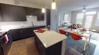 This 2-bedroom, 2-bathroom residence offers a thoughtfully designed single-level layout that balances modern style with everyday functionality. The open-concept kitchen is a standout feature, showcasing dark espresso cabinetry, granite countertops, a subway tile backsplash, and a full suite of stainless steel appliances including a refrigerator, range, and microwave. A central granite-topped island with bar seating serves as a natural gathering point and flows seamlessly into the dining and living areas, which are finished with warm wood-style flooring throughout. The living room benefits from natural light and provides a comfortable, versatile space. Both bedrooms feature plush carpeting, ceiling fans, and windows that invite natural light. Walk-in closets with wire shelving systems provide ample storage. The primary bathroom includes a double-sink vanity with granite counters, dark cabinetry, and hardwood-style flooring, while the second bathroom offers a tub-shower combination with granite countertops and matching dark cabinetry. The overall design maintains a cohesive contemporary aesthetic with neutral tones, quality finishes, and a practical layout suited for comfortable residential living.