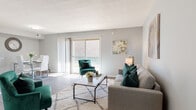 This single-floor residence offers a thoughtfully designed layout that balances comfort and functionality throughout. The living room serves as the heart of the home, featuring light hardwood-style flooring, soft neutral walls, and a large sliding glass door that floods the space with natural light and provides a view to the outdoors. A patterned area rug and stylish furnishings in grey and emerald green lend the room a contemporary, inviting ambiance.

Adjacent to the living area, the dedicated dining space accommodates a glass-top table with modern white chairs, set against cool grey walls with dark hardwood-style flooring — ideal for everyday meals or entertaining.

The kitchen is clean and contemporary, showcasing white shaker-style cabinetry, white quartz countertops, a classic subway tile backsplash, and stainless steel appliances including a dishwasher, range, and microwave — offering both style and practicality.

The two bedrooms are generously proportioned, each featuring plush carpet flooring and ample closet space. The primary bedroom includes a wall-mounted television and connects conveniently to adjoining rooms. The second bedroom is bright and relaxing, with a window and tasteful décor.

The bathroom is finished in a clean, modern style with a white vanity, brushed nickel fixtures, and a shower-tub combination.