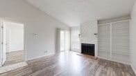 This single-story, 1-bedroom, 2-bathroom residence in Round Rock, Texas, offers a well-designed layout with modern finishes throughout. The living room serves as the heart of the home, showcasing vaulted ceilings, wood-style flooring, and a striking white diagonal wood-paneled fireplace flanked by built-in open shelving. Sliding glass doors with vertical blinds flood the space with natural light and provide access to the private patio. The galley-style kitchen features dark cabinetry with contrasting white countertops, stainless steel appliances including a refrigerator and range, and matching wood-style flooring that carries throughout the home. The bedroom is a comfortable retreat with a ceiling fan, a sliding glass door to the patio, and ample closet storage — four closets are distributed throughout the unit. The bathrooms are finished with dark vanity cabinetry, elegant marble-look countertops, brushed nickel fixtures, and a tub-shower combination. Neutral tones, textured ceilings, and consistent flooring create a cohesive, clean aesthetic throughout this efficiently planned home in the Round Rock community.