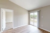 Located at 2200 Montgomery Park Blvd in Conroe, TX, this single-floor, 1-bedroom, 2-bathroom residence offers a thoughtfully designed layout with modern finishes throughout. The open-concept kitchen is a standout feature, showcasing gray shaker-style cabinetry, a white peninsula countertop with a built-in sink, stainless steel appliances including an electric range and dishwasher, and a black refrigerator. Recessed lighting and wood-look vinyl flooring complete the contemporary look of this functional cooking space. The living area flows naturally from the kitchen, providing an open and connected feel. The generously sized primary bedroom features plush carpeting, a ceiling fan, and a sliding glass door that opens to a private balcony with views of the surrounding tree-lined neighborhood. The walk-in closet offers built-in shelving and hanging rods for ample storage. Both bathrooms are finished with wood-look flooring and brushed gold fixtures, with one featuring a tub-shower combination with clean white tile surround. The private balcony extends the living space outdoors, offering a relaxed view of the landscaped grounds and green canopy beyond.