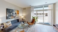 Located at 401–441 S Rose St in downtown Kalamazoo, Michigan, this single-floor unit offers a thoughtfully designed open-concept layout with modern finishes throughout. Light wood-look flooring flows continuously across the living, dining, and kitchen areas, creating a cohesive and airy feel.

The kitchen is well-appointed with two-tone cabinetry—glossy white upper cabinets paired with warm wood lower cabinets—complemented by granite countertops and a full suite of stainless steel appliances, including a refrigerator, electric range, and over-the-range microwave. A kitchen island provides additional counter space and casual seating.

The living area is bright and welcoming, featuring large floor-to-ceiling windows that invite abundant natural light and offer views of the surrounding urban streetscape. The open layout allows for comfortable furniture arrangements and a relaxed atmosphere.

The bedroom is generously proportioned, featuring oversized windows with city views, a sliding closet with built-in shelving, and soft neutral tones that contribute to a calm, restful environment.

The bathroom is finished with large-format tile in a neutral stone tone, a glass-enclosed walk-in shower with a built-in niche, and light wood-look flooring that ties seamlessly to the rest of the unit. Overall, the space presents a clean, contemporary aesthetic well-suited to urban living.