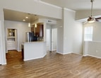 Unit #1814 at Bell Starwood in Frisco, TX is a well-appointed 2-bedroom, 2-bathroom residence spanning 960 square feet across two floors. The main living level features an open-concept kitchen and living room with warm wood-look hardwood flooring, crown molding, and a classic white-mantled fireplace flanked by multiple windows that bring in abundant natural light. The kitchen is equipped with rich dark wood cabinetry, granite countertops, a tile backsplash, and stainless steel appliances including a refrigerator and dishwasher. A dedicated in-unit laundry room with full-size washer and dryer hookups adds everyday convenience. Both bedrooms are carpeted and feature ceiling fans, crown molding, and ample natural light. The primary bedroom measures 140 square feet and includes a walk-in closet outfitted with wire shelving. Each bathroom is finished with dark wood vanities, granite countertops, and tub-shower combinations with wood-look flooring. A second closet provides additional storage. The entry level offers a welcoming foyer with soaring ceilings, hardwood-style flooring, and direct outdoor access through a windowed door. Crown molding and neutral tones throughout lend a clean, cohesive aesthetic to the entire unit.