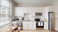 Located at 4021 Ridge Ave in Philadelphia's East Falls neighborhood, this thoughtfully designed one-bedroom, one-bathroom unit maximizes every inch of its compact footprint. Light hardwood flooring flows throughout, tying together the clean, contemporary aesthetic.

A welcoming hallway lined with closet storage leads into the heart of the unit. The kitchen is a true highlight, featuring crisp white shaker cabinetry, granite-style countertops, a classic white subway tile backsplash, and a full suite of stainless steel appliances — including a dishwasher, range, microwave, and refrigerator. A cozy dining nook with large windows fills the kitchen area with abundant natural light and neighborhood views.

The bedroom offers a comfortable, versatile layout, accommodating both a bed and a seating area with ease. A ceiling fan, recessed lighting, and a bright window contribute to the room's airy feel. Two closets provide generous storage for the unit's size.

The bathroom is elegantly finished with large-format marble-style tile on both the floors and shower surround, paired with a white vanity topped with granite-style counters. An in-unit laundry area adds everyday convenience. Overall, the unit delivers a refined, move-in-ready living experience.