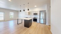 Located at 352 S 500 E in Salt Lake City's vibrant East Side neighborhood, this modern 2-bedroom, 2-bathroom residence offers a thoughtfully designed single-level layout finished with light hardwood flooring and crisp white walls throughout. The open-concept kitchen and living area serves as the heart of the home, featuring white cabinetry, a herringbone-patterned tile backsplash, quartz countertops, a stainless steel appliance suite including a refrigerator, range, microwave, and dishwasher, and a striking dark-finished island with pendant lighting above. The living area flows naturally from the kitchen and includes a glass door opening to an outdoor balcony, filling the space with natural light. The spacious primary bedroom offers ample room and connects to a well-appointed ensuite bathroom featuring a dual-sink vanity with backlit mirrors and a glass-enclosed shower. The second bathroom includes a full soaking tub and shower combination with a single vanity. Both bedrooms are bright, with windows allowing in generous daylight. A dedicated closet and in-unit stacked washer and dryer add everyday convenience. The clean, contemporary aesthetic and efficient use of space make this residence a highly functional and modern urban home.
