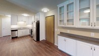 This single-floor unit at 3201 W 43rd St in Sioux Falls, South Dakota, offers a practical and well-appointed layout designed for comfortable everyday living. The kitchen is a standout feature, equipped with stainless steel appliances including a range, microwave, dishwasher, and refrigerator. White cabinetry extends to the ceiling, providing generous storage, while granite-style countertops and a double stainless steel sink add a polished finish. Dark hardwood-style flooring runs throughout the kitchen and main living areas, creating a cohesive and easy-to-maintain aesthetic.

Adjacent to the kitchen, a dining or flex area features a built-in white cabinetry unit with glass-front upper cabinets and a dark countertop, offering additional storage and display space. The open layout connects seamlessly to the main living area, which benefits from flush-mount lighting and a textured ceiling.

The two bedrooms are carpeted and share a neutral warm-toned palette, each featuring a window with blinds that allows natural light in alongside baseboard heating for year-round comfort. The full bathroom includes a single-sink vanity with granite-style countertops, white cabinetry, a full tub-shower combination, and dark hardwood-style flooring, maintaining consistency with the rest of the unit.